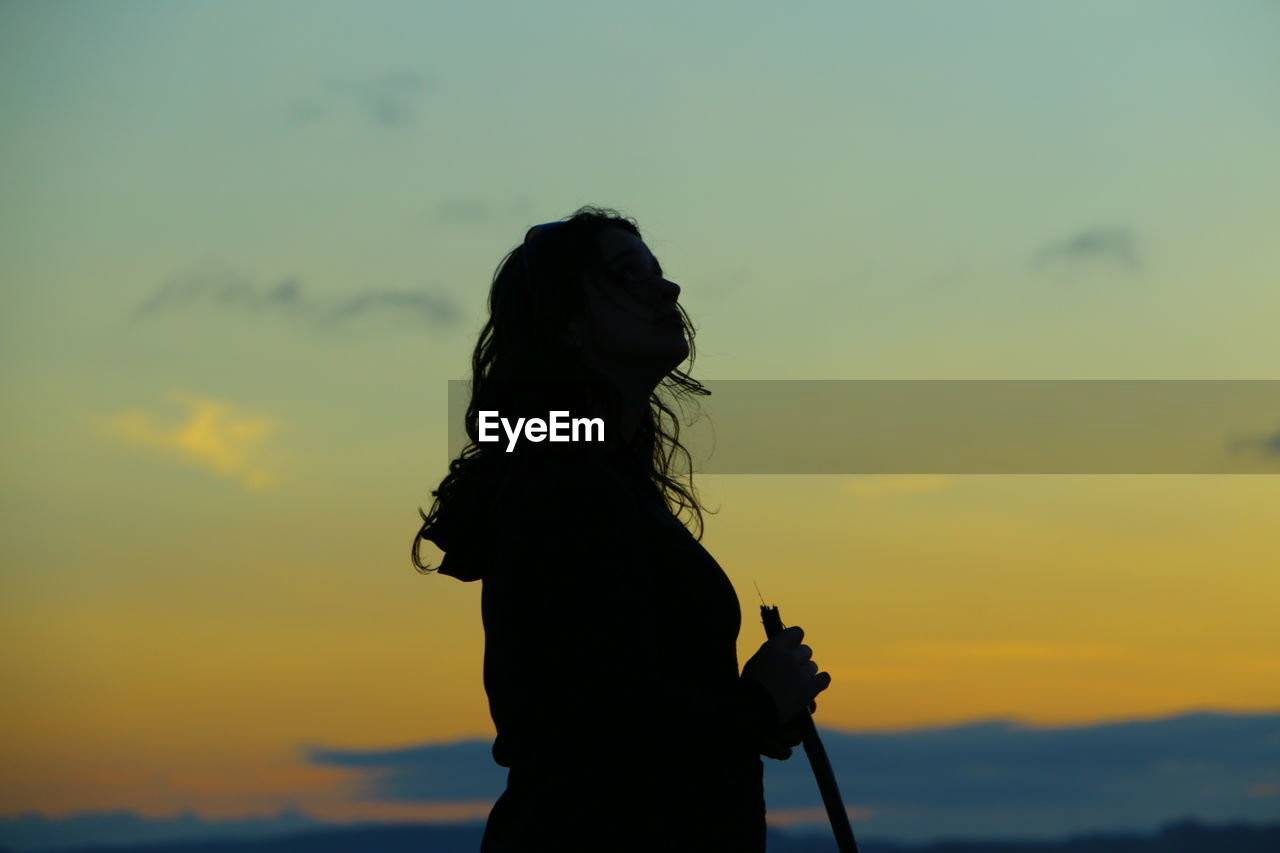 Silhouette woman standing against sky during sunset