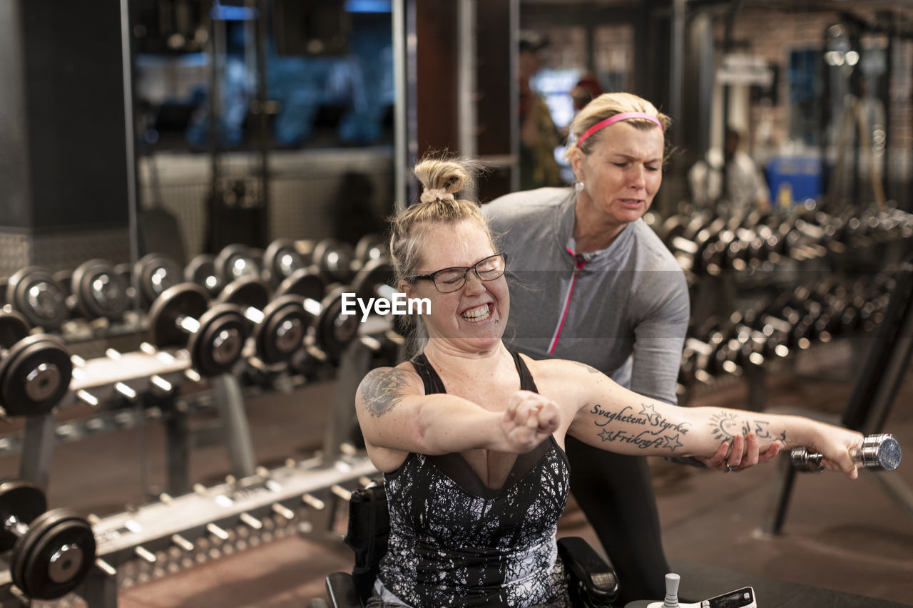 Woman on wheelchair training in gym with personal trainer
