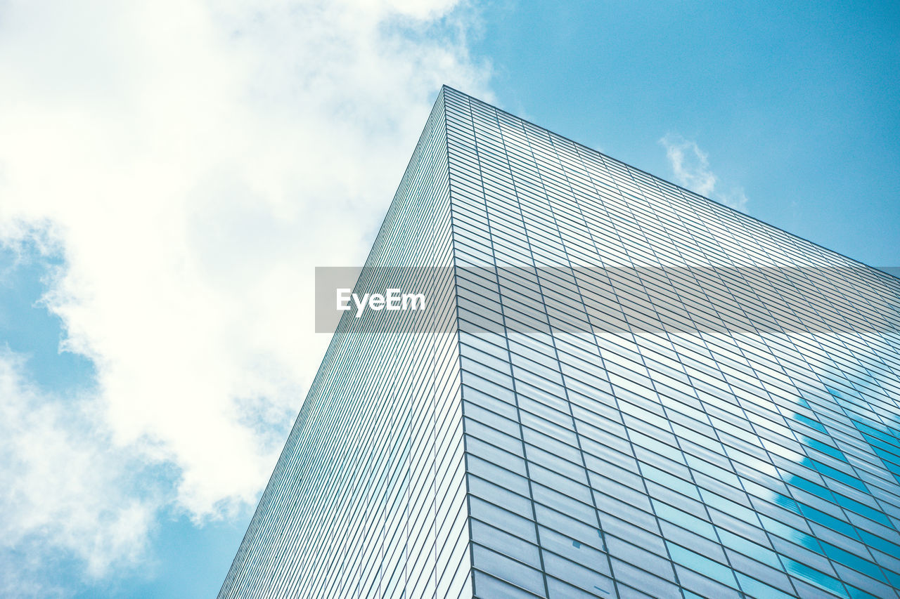 LOW ANGLE VIEW OF MODERN GLASS BUILDING AGAINST SKY