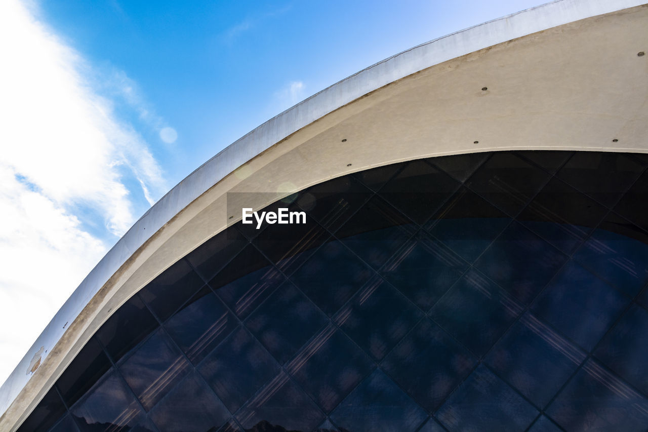 LOW ANGLE VIEW OF MODERN GLASS BUILDING AGAINST SKY