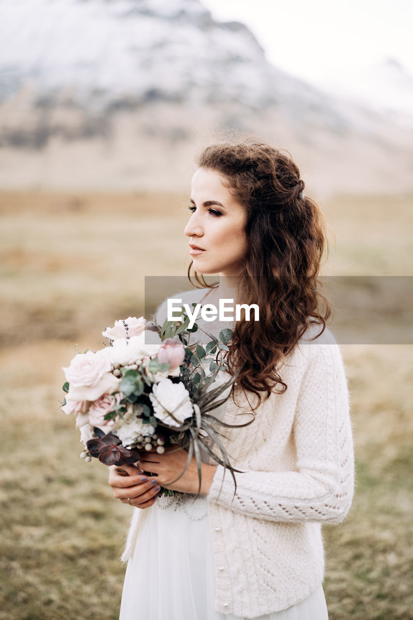 Beautiful woman standing by flowering plant