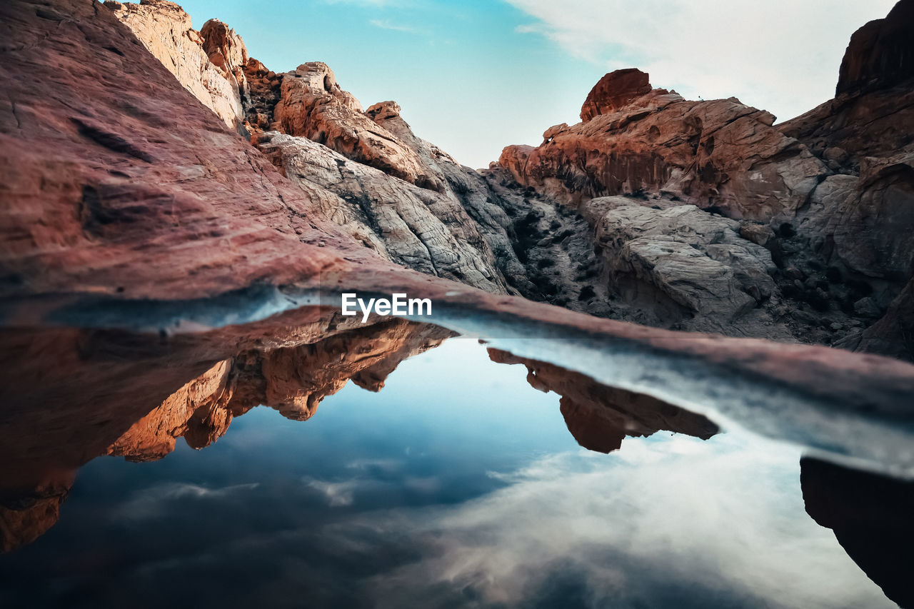 Scenic view of mountains reflecting in water against sky