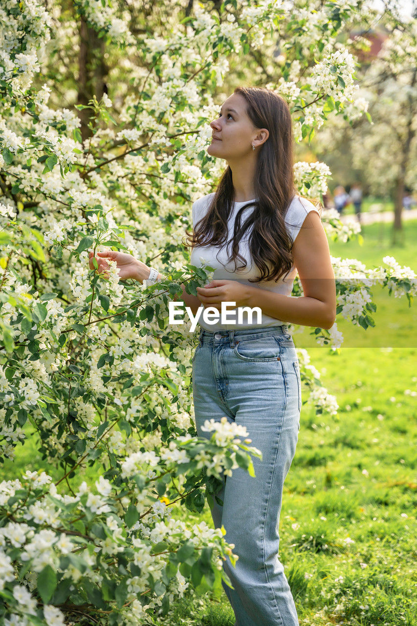 portrait of smiling young woman standing against plants