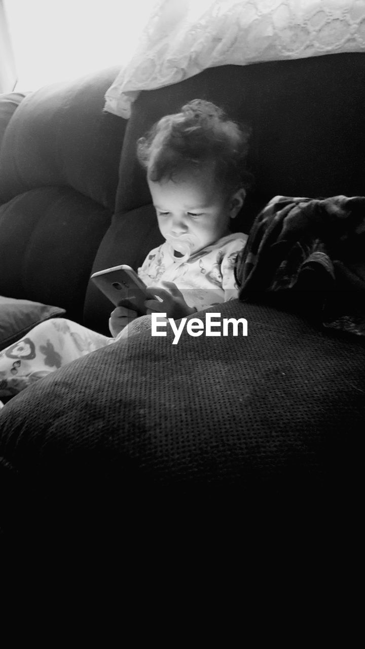 Boy using mobile phone while sitting on sofa at home