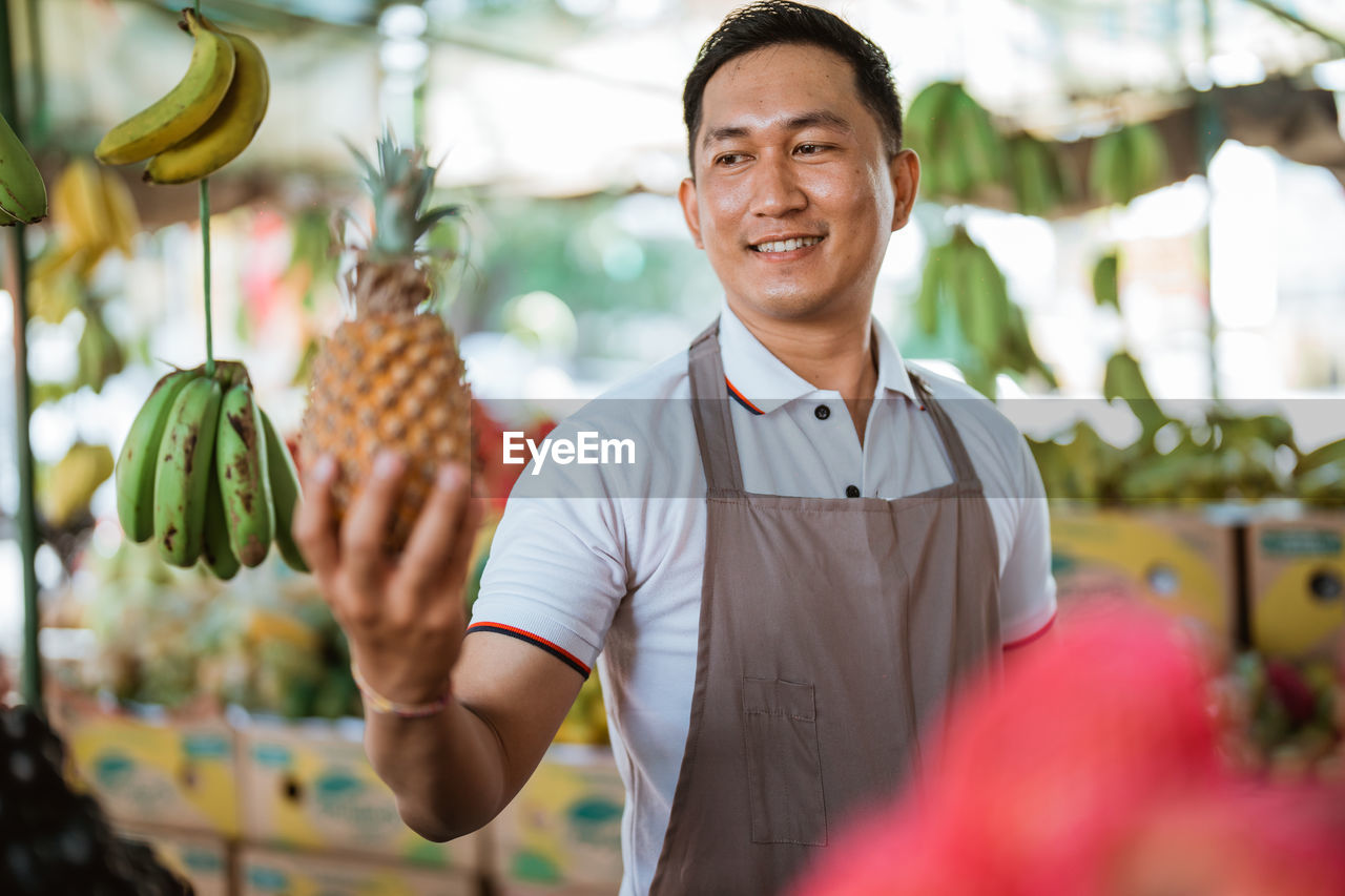 portrait of young man holding pineapple