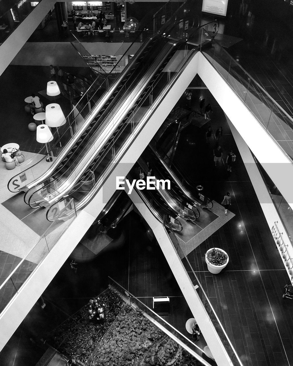 HIGH ANGLE VIEW OF ESCALATOR IN GLASS AT SHOPPING MALL