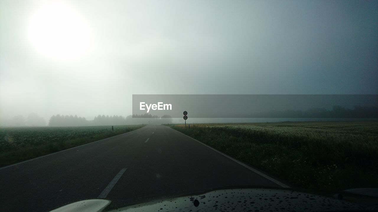 Cropped image of car on road against sky during foggy weather