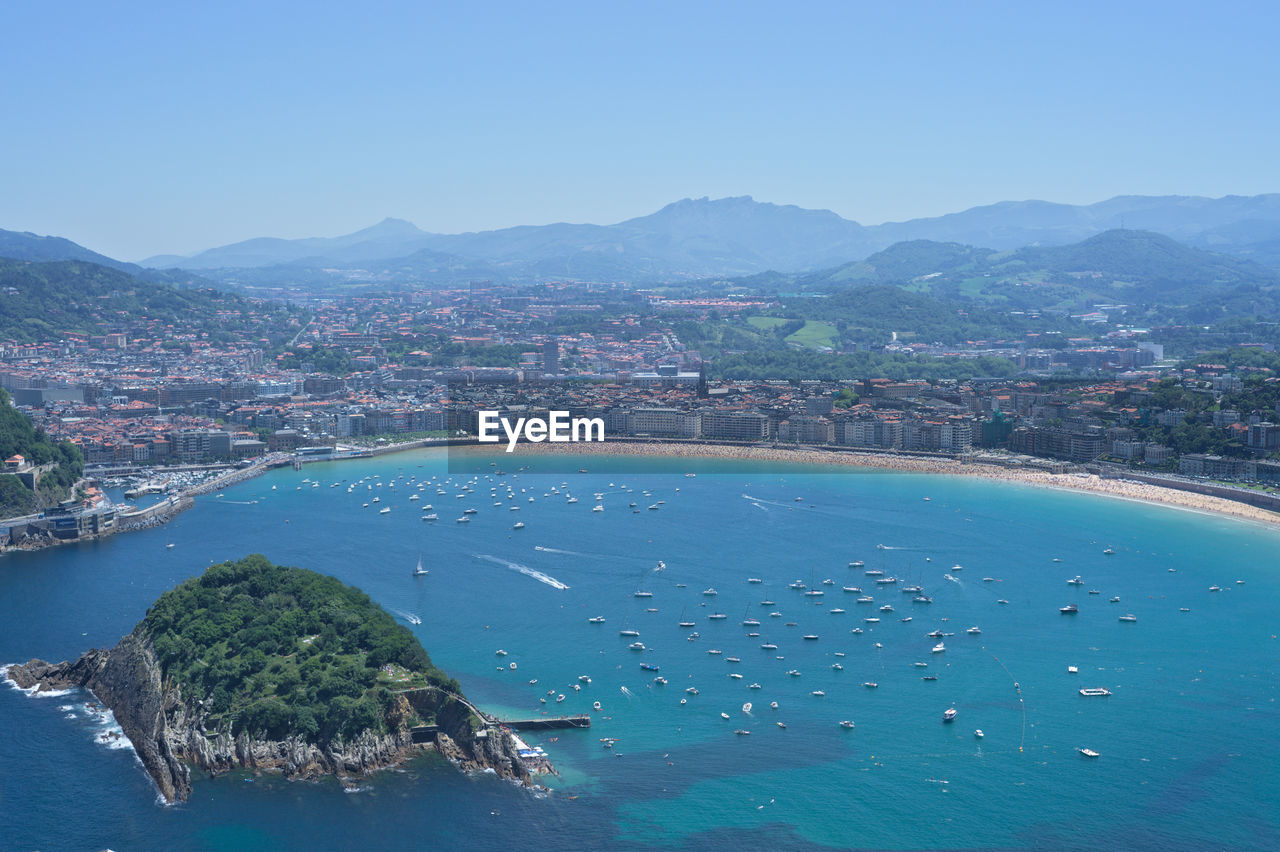 Aerial view of cityscape and mountains against clear blue sky