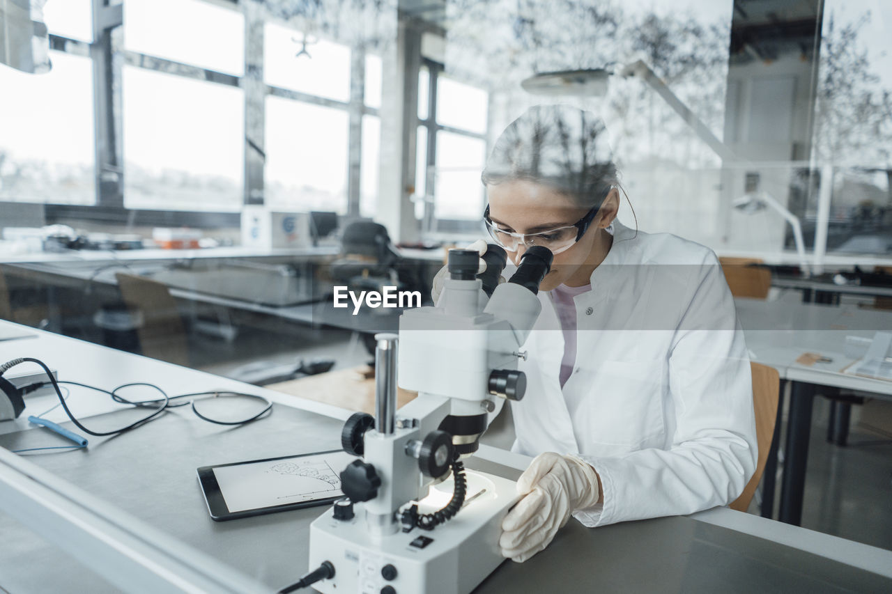 Young scientist working on microscope in laboratory