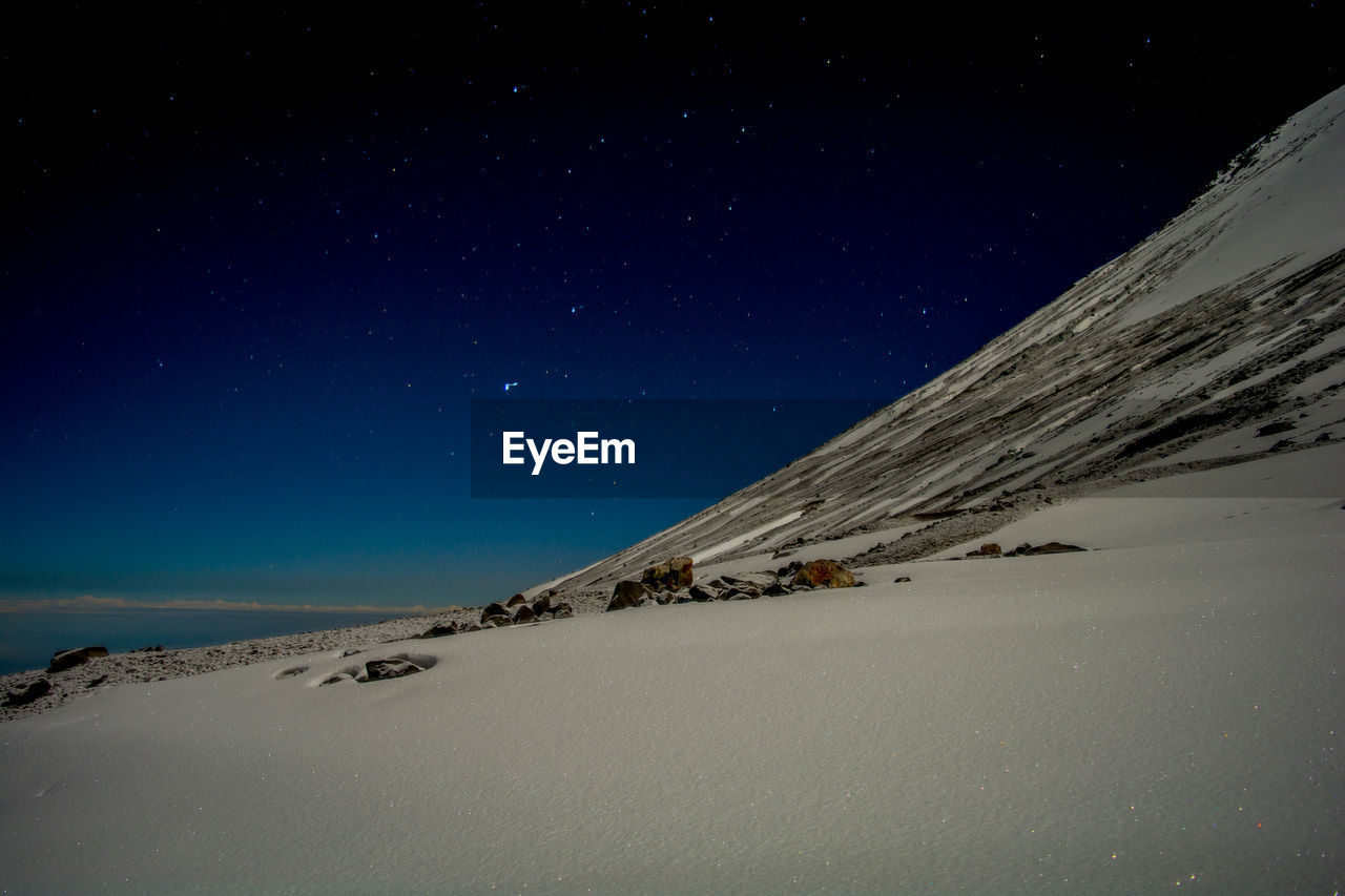 Scenic view of snowy mountain against starry sky