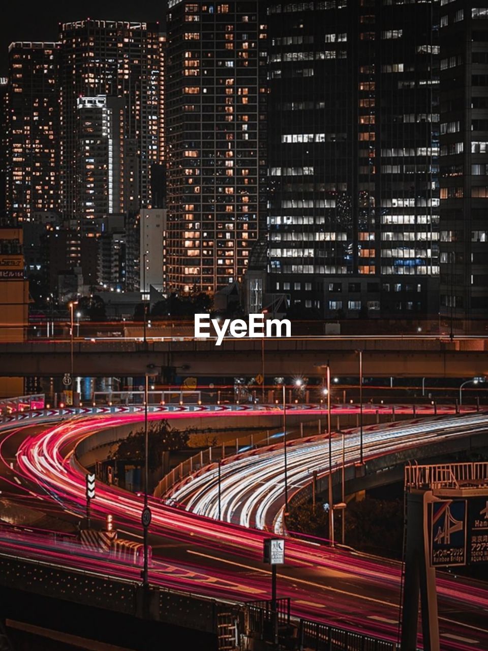 Light trails on road against illuminated buildings in city