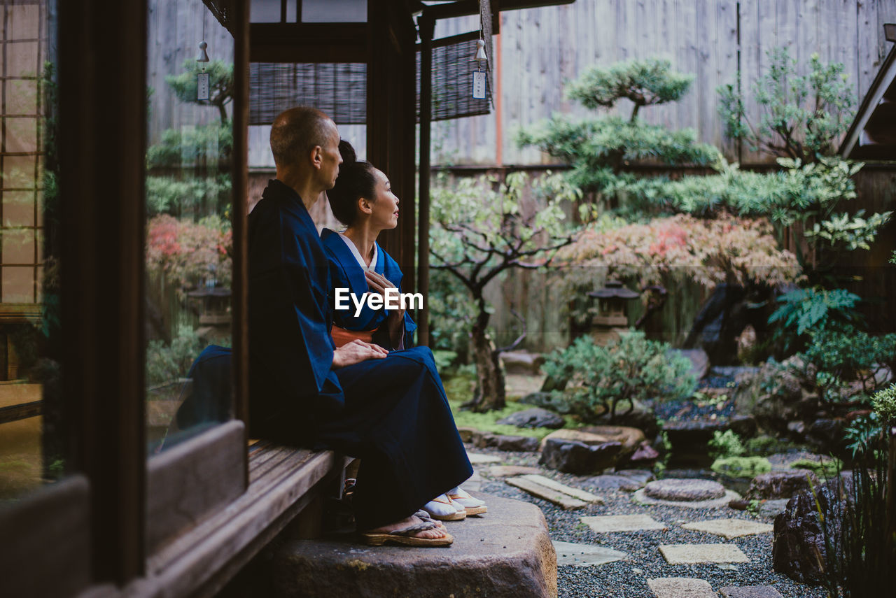 Couple sitting on wall outdoors