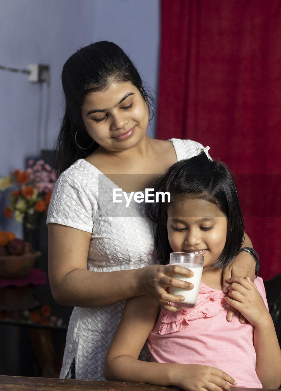 An indian asian mother giving glass of milk to her daughter