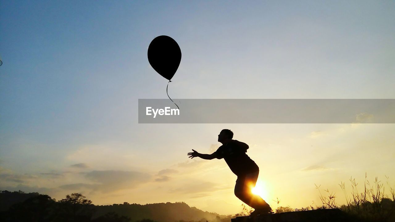 SILHOUETTE OF MAN PLAYING WITH BALL AGAINST SKY