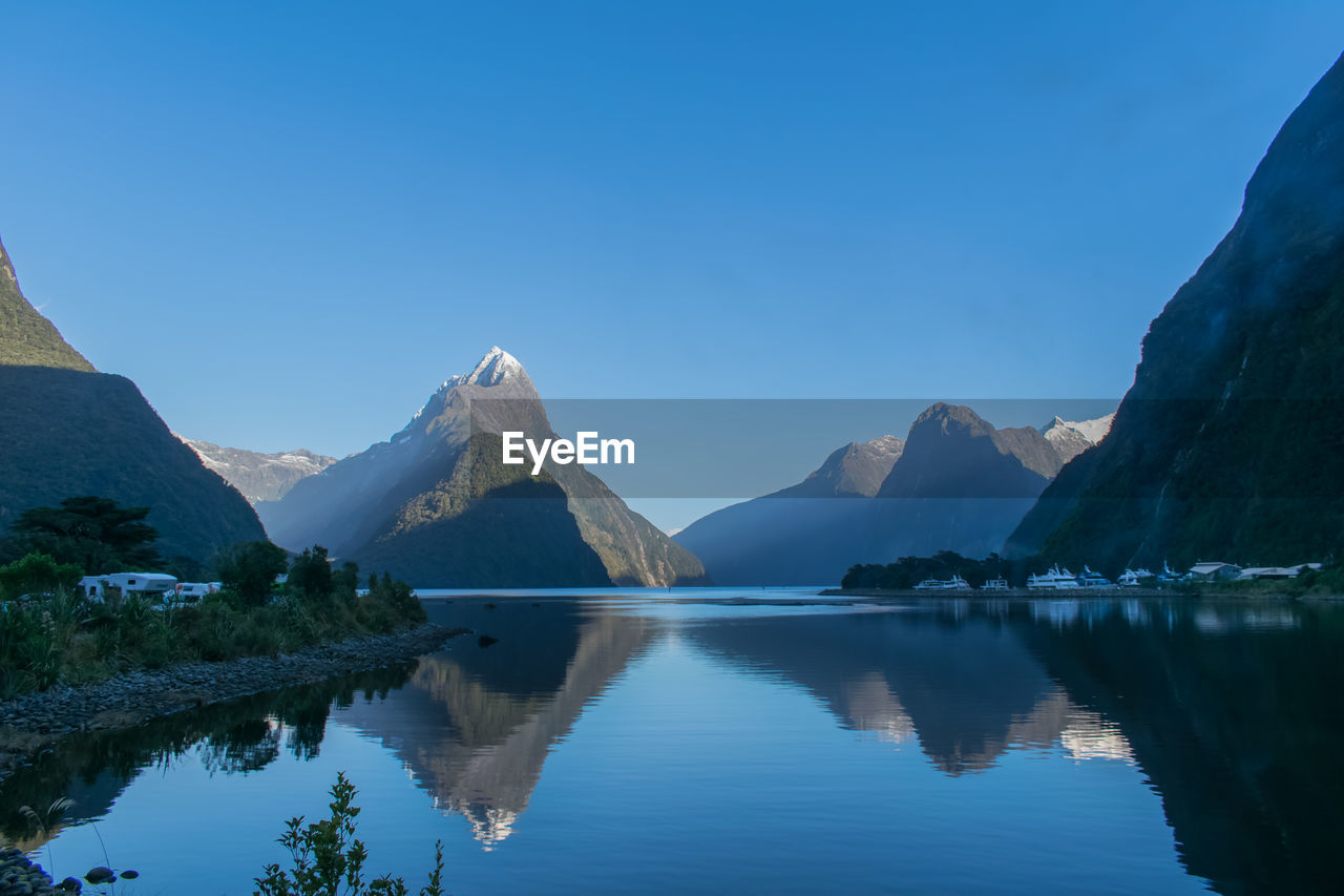 Scenic view of lake and mountains against clear blue sky