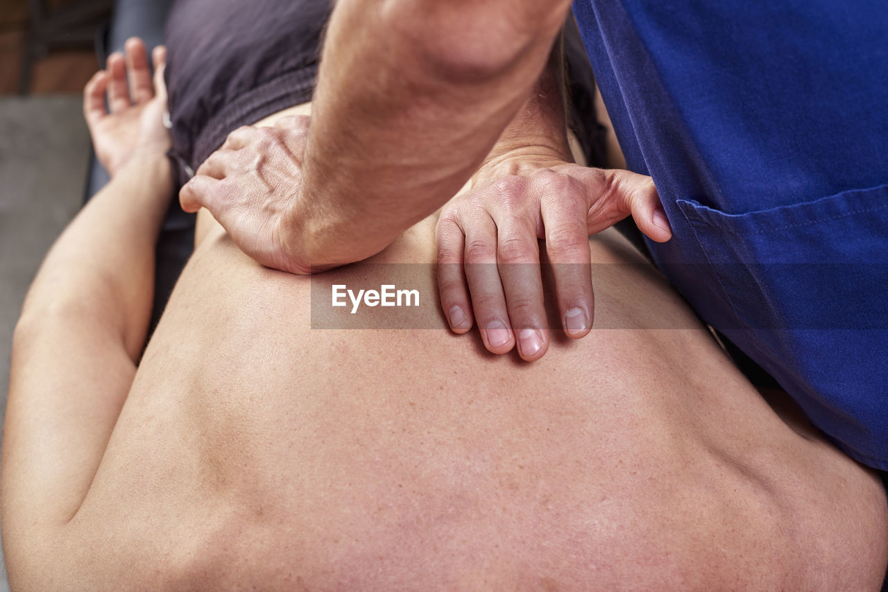 Midsection of man giving osteopath treatment to patient lying at clinic