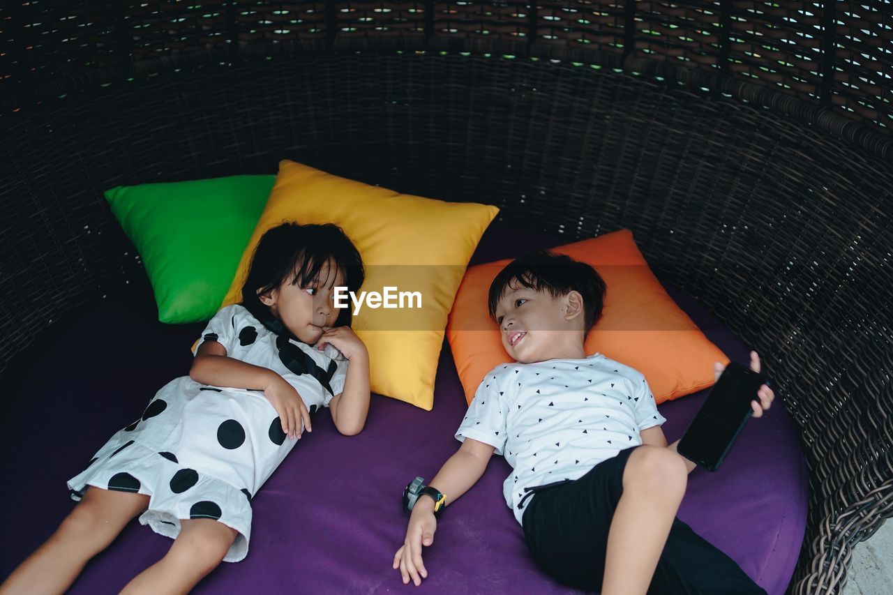 High angel view of cute sibling lying down on bed