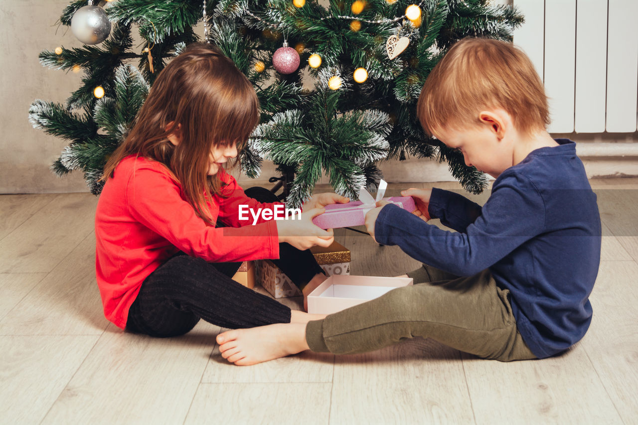 Joyful children open new year's gifts under the christmas tree. christmas holiday. 