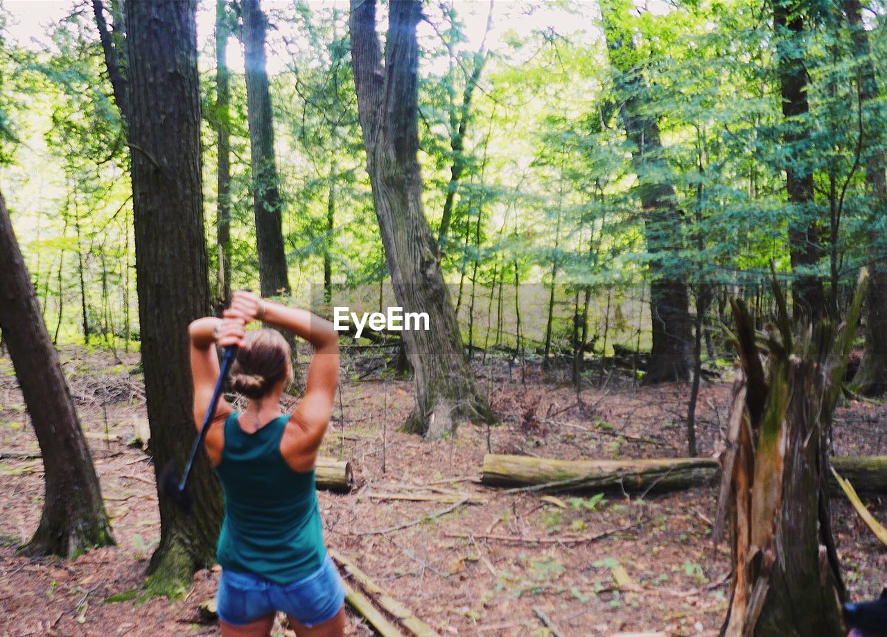 REAR VIEW OF YOUNG WOMAN PHOTOGRAPHING IN FOREST