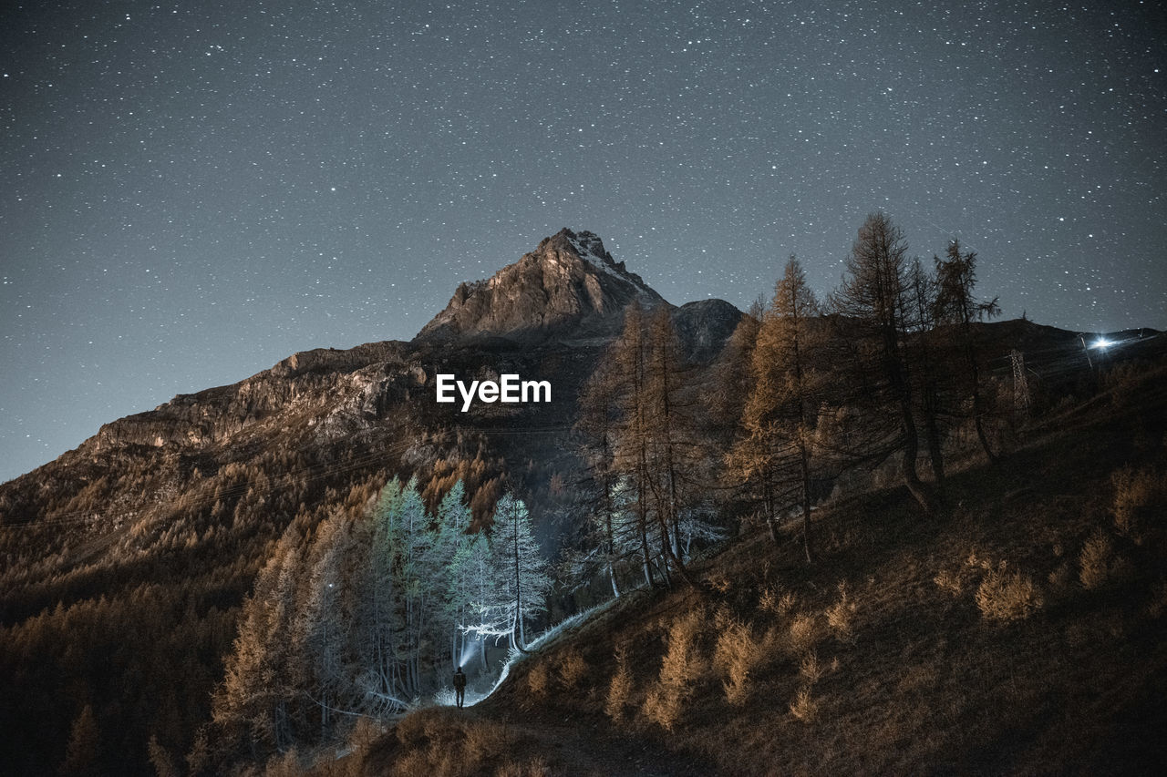 View of a summit and a person against sky at night