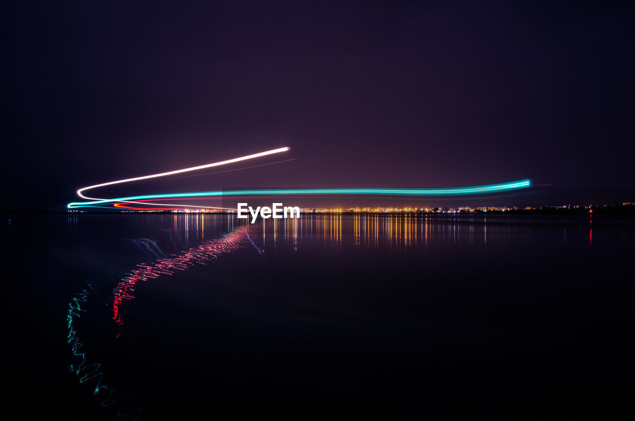 Illuminated bridge over river against sky at night