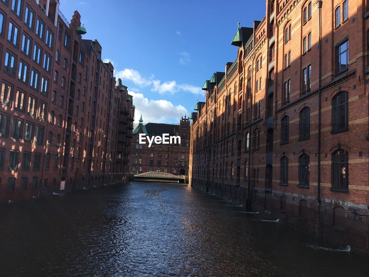 BRIDGE OVER CANAL AMIDST BUILDINGS IN CITY