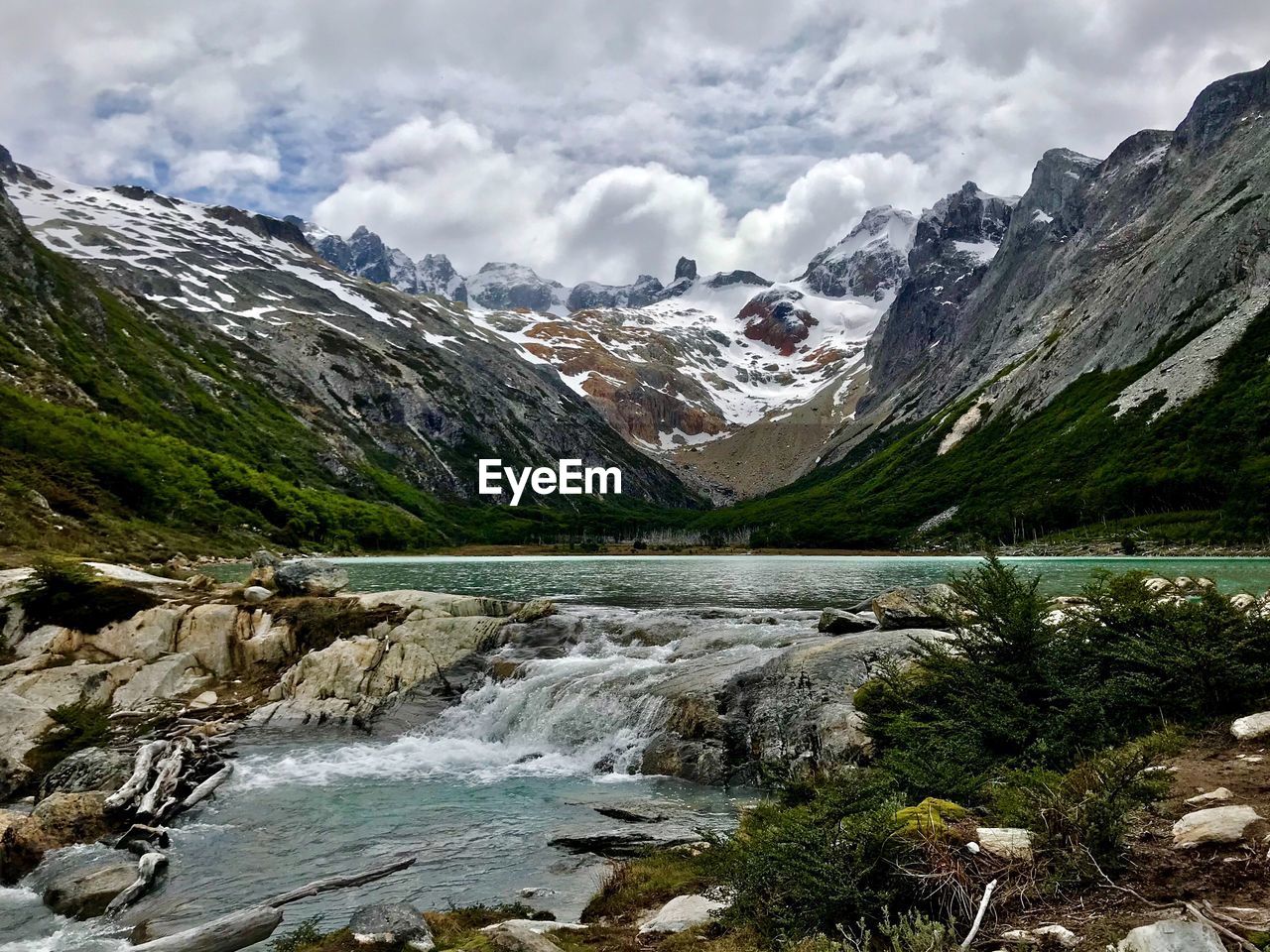 Scenic view of river and mountains against cloudy sky