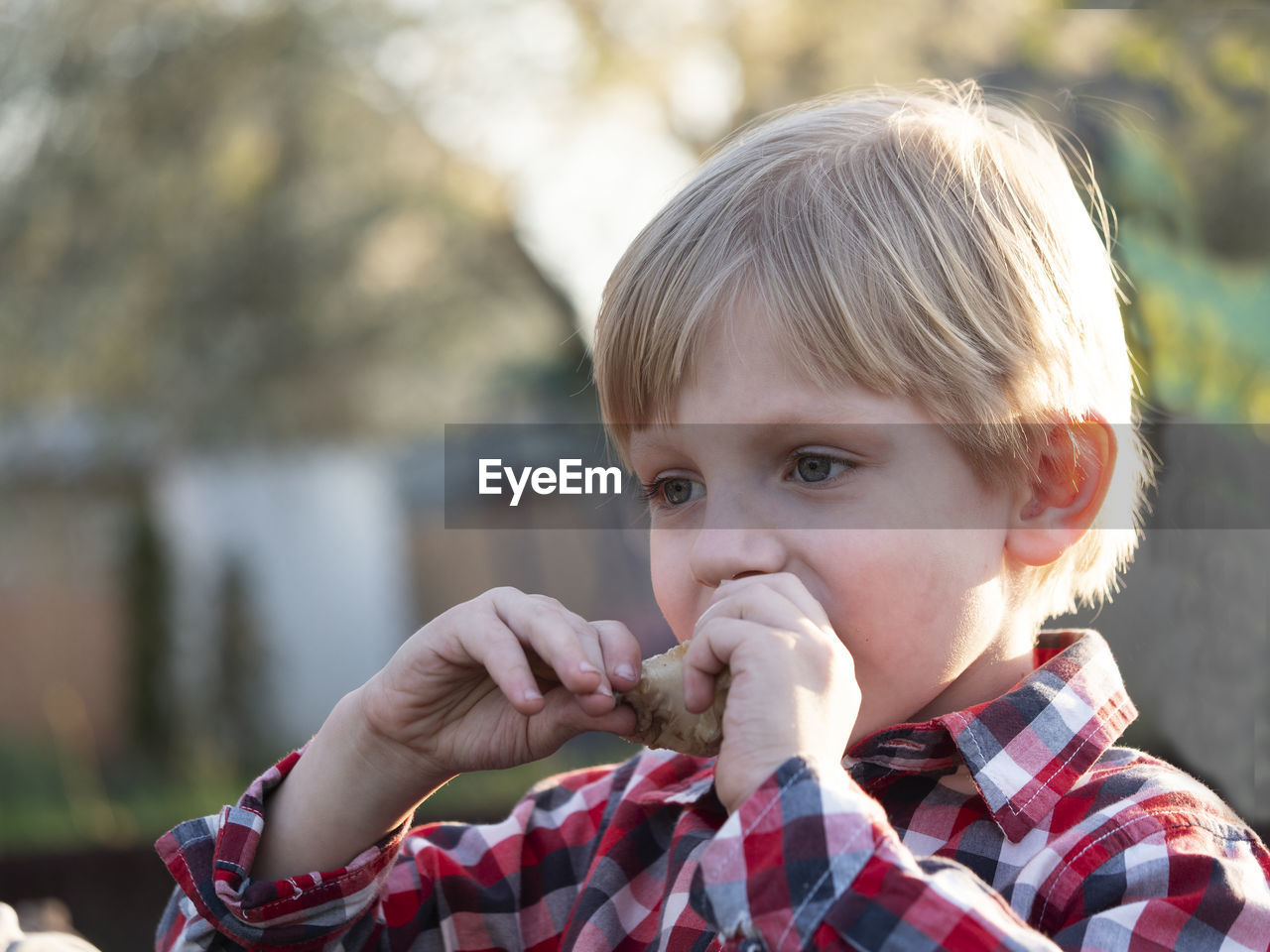 Caucasian boy eats a chicken drumstick cooked on the bbq delicious