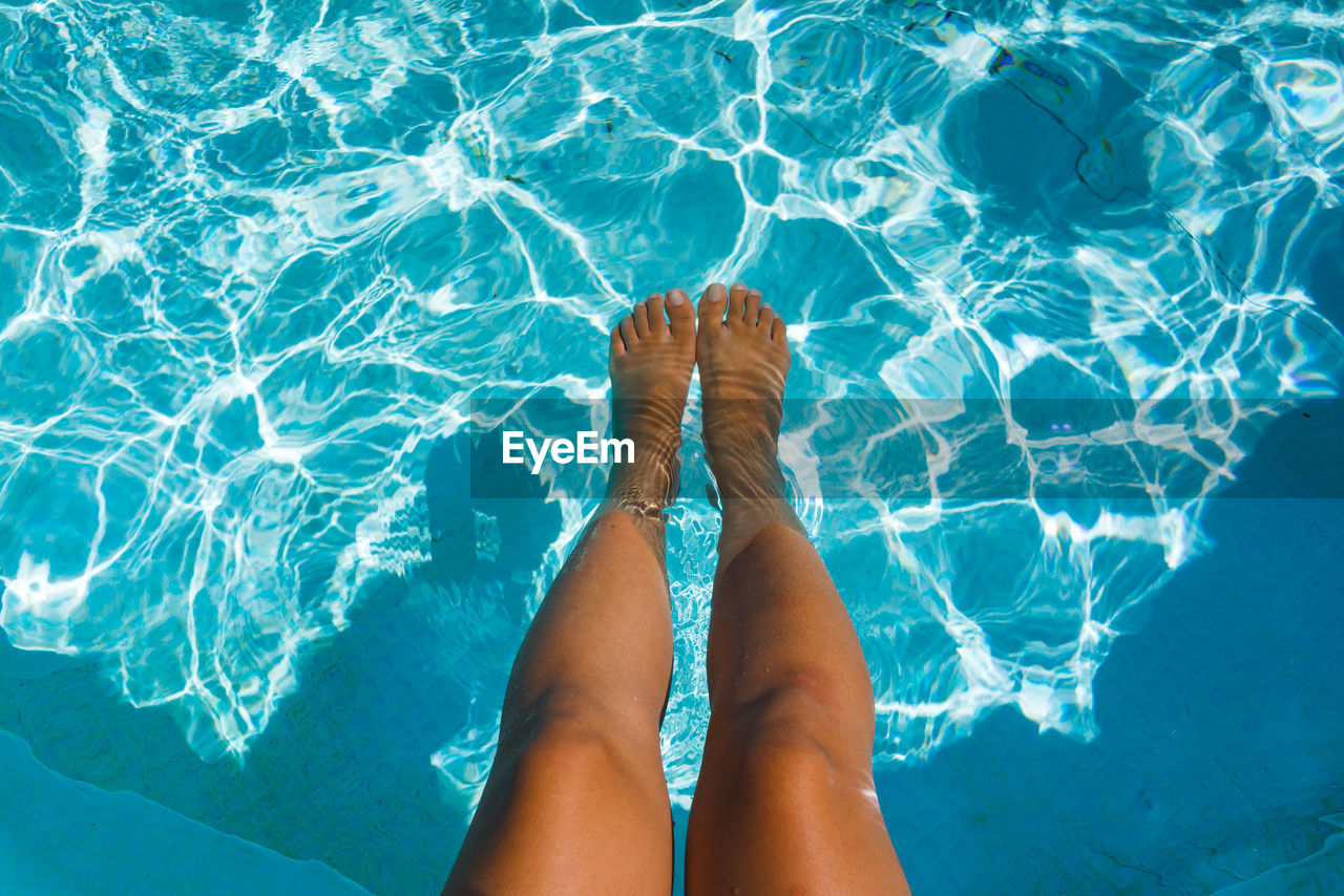 Low section of woman relaxing in swimming pool