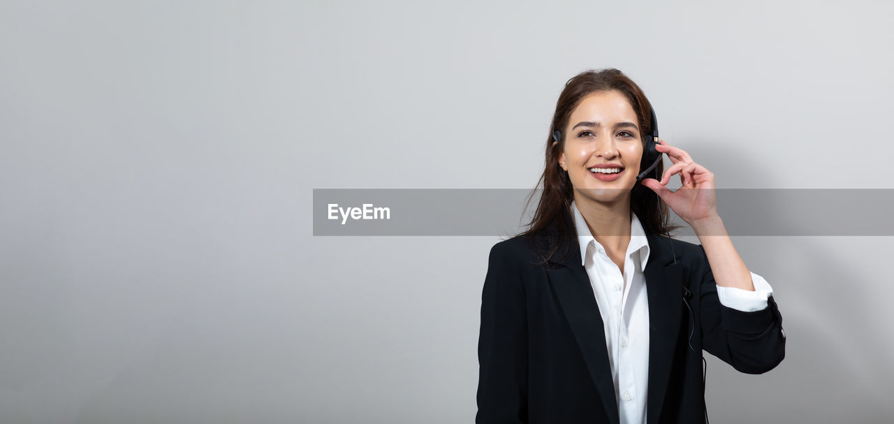 PORTRAIT OF SMILING YOUNG WOMAN USING PHONE