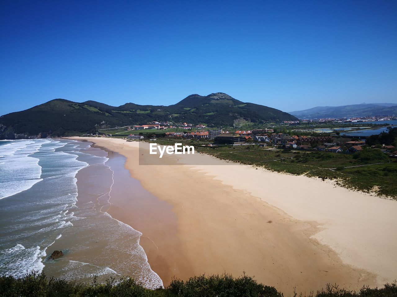 Scenic view of beach against clear blue sky