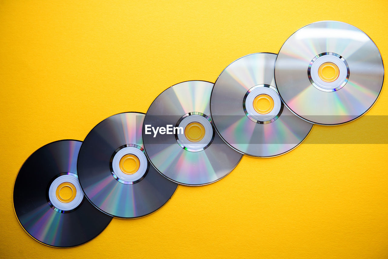 Close-up of compact discs over yellow background