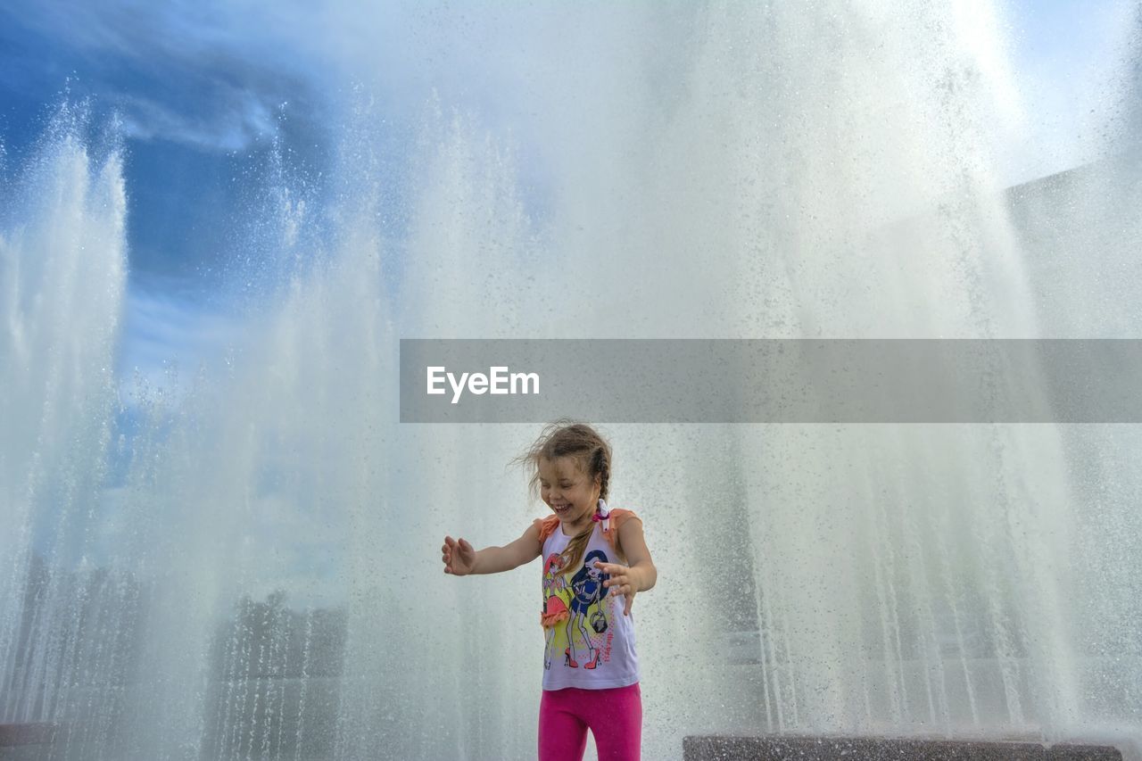 Happy girl standing against fountain 