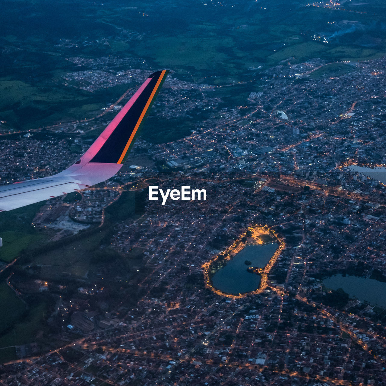 Cropped image of airplane wing flying over cityscape at dusk