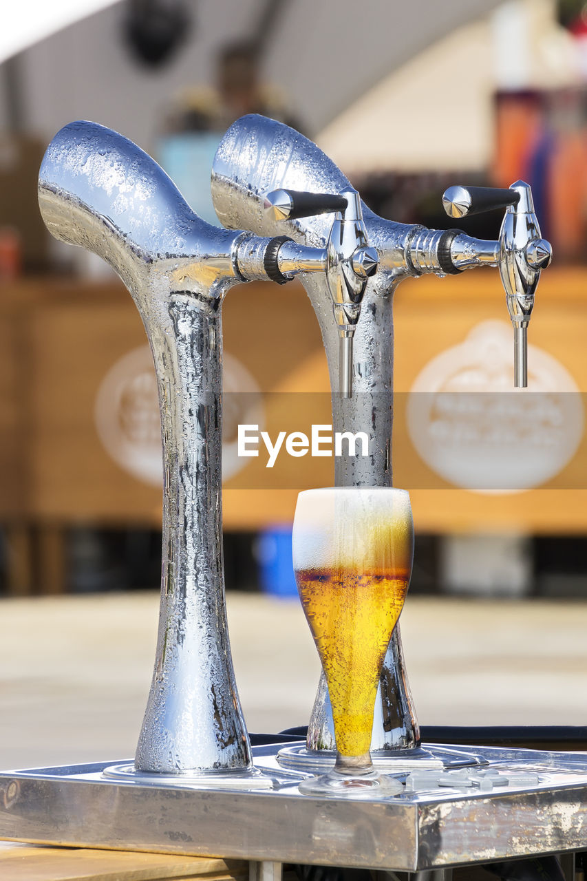 Close-up of glass under beer tap 