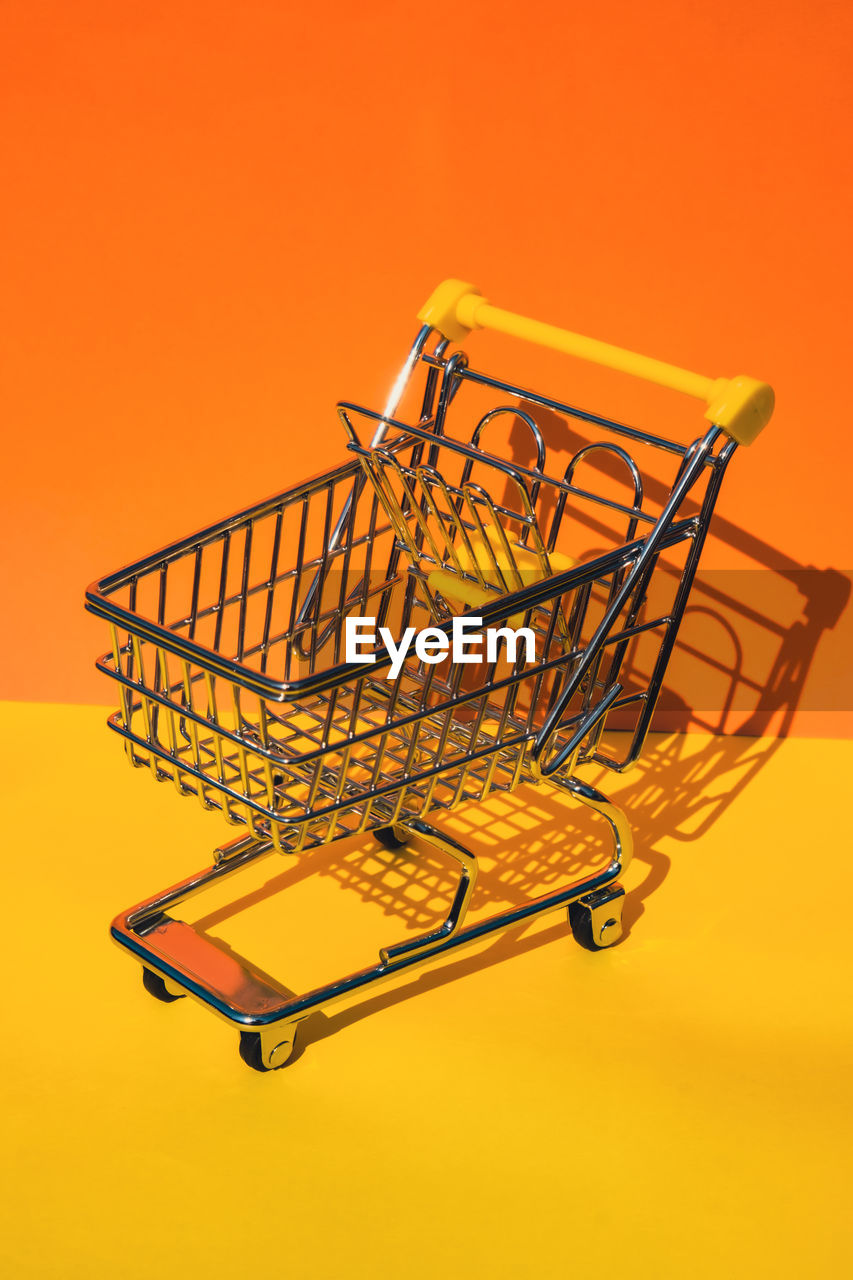 Empty shopping trolley cart on colorful orange yellow background. copy space for your text. online