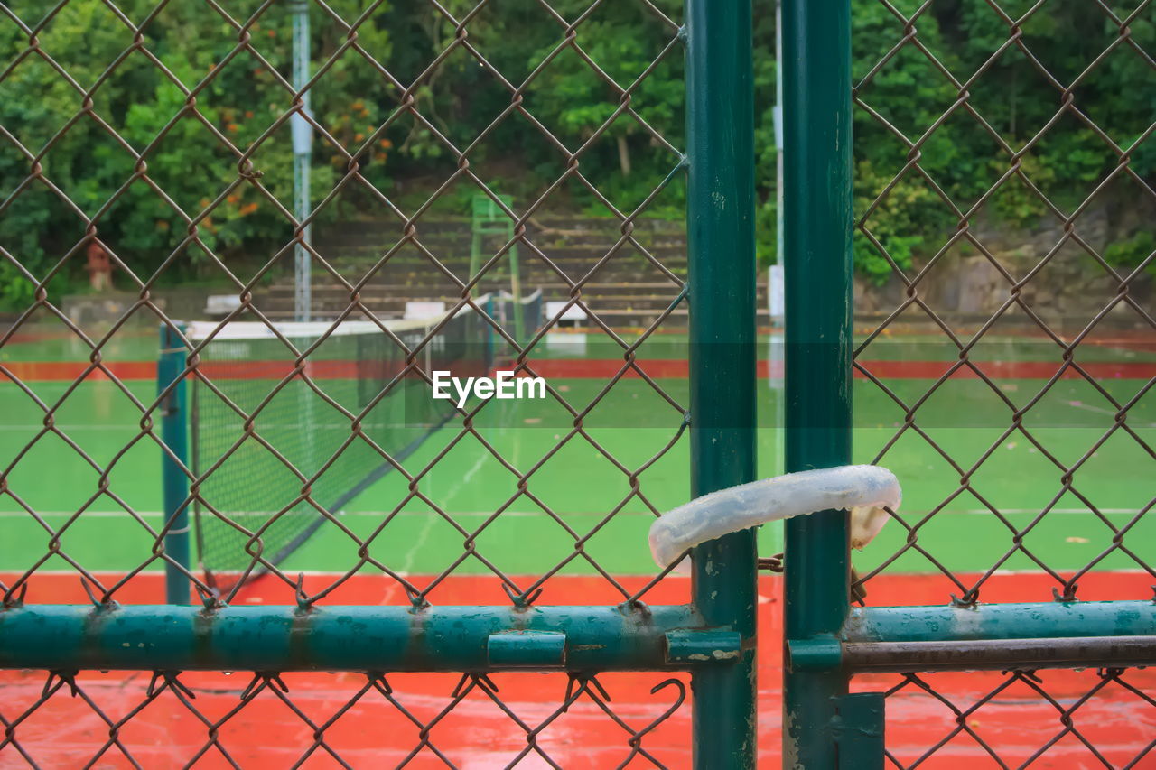 Close-up of chainlink fence against tennis court