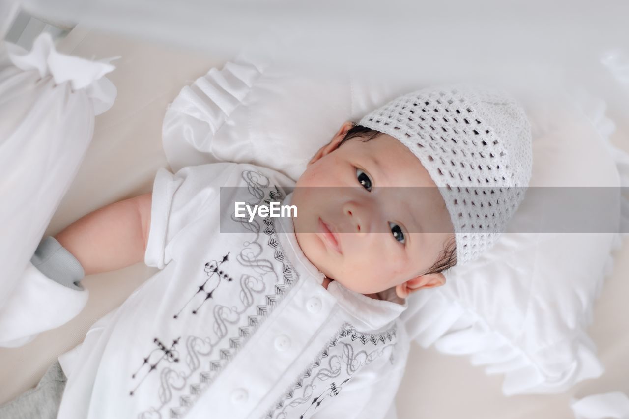 Portrait of cute baby lying on bed at home