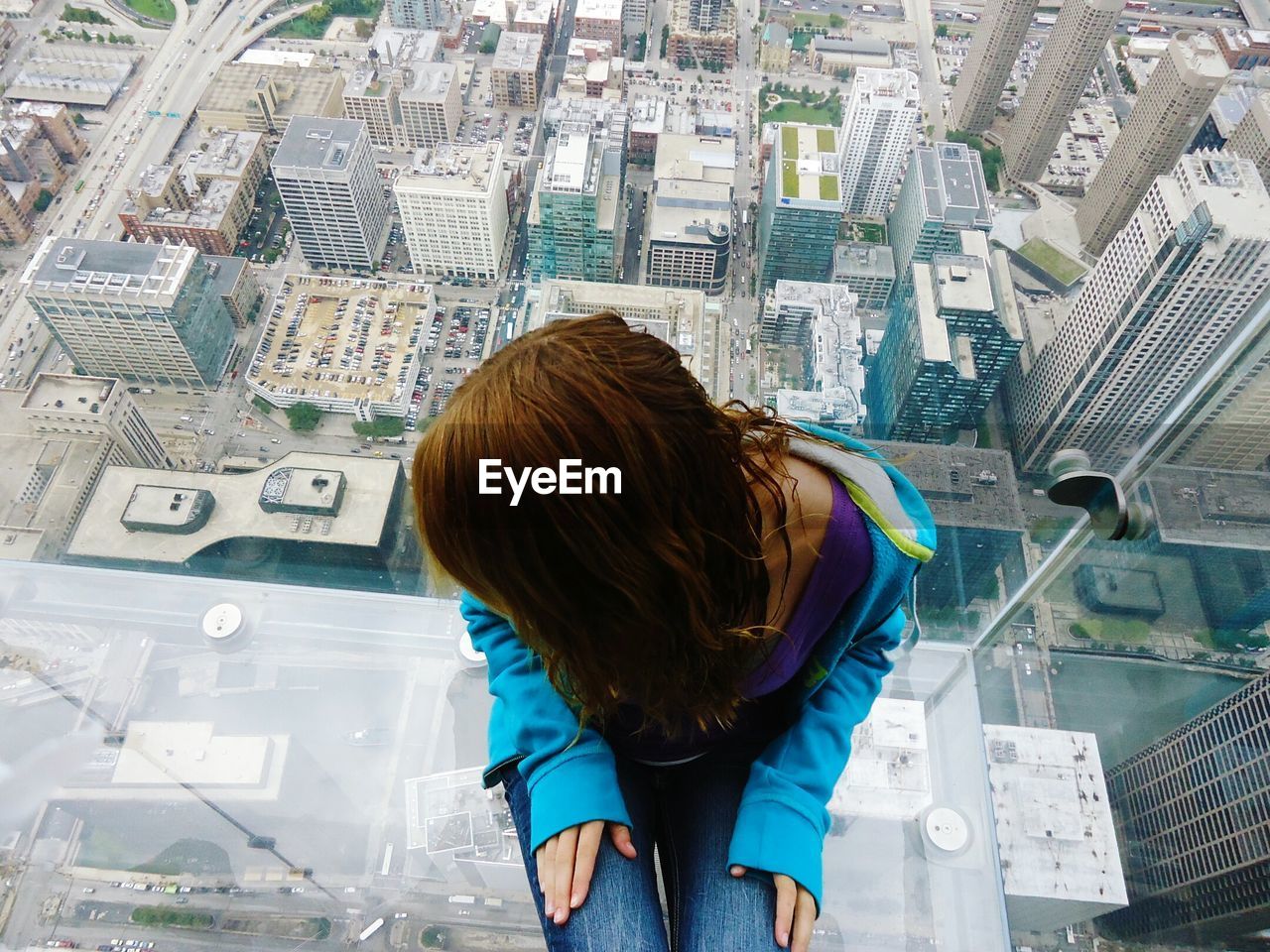 High angle view of woman sitting at window looking at cityscape