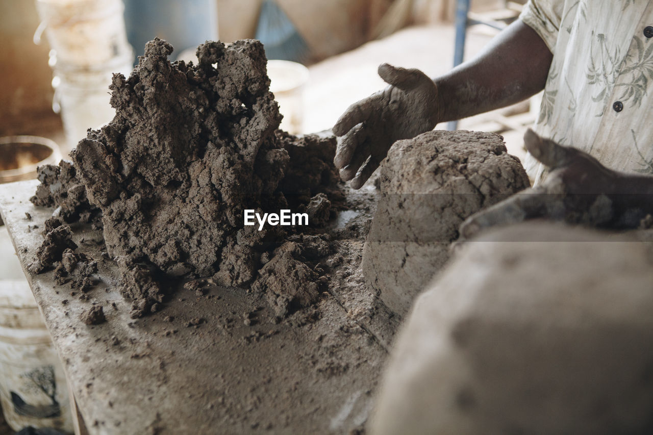 Midsection of worker kneading clay at table in workshop