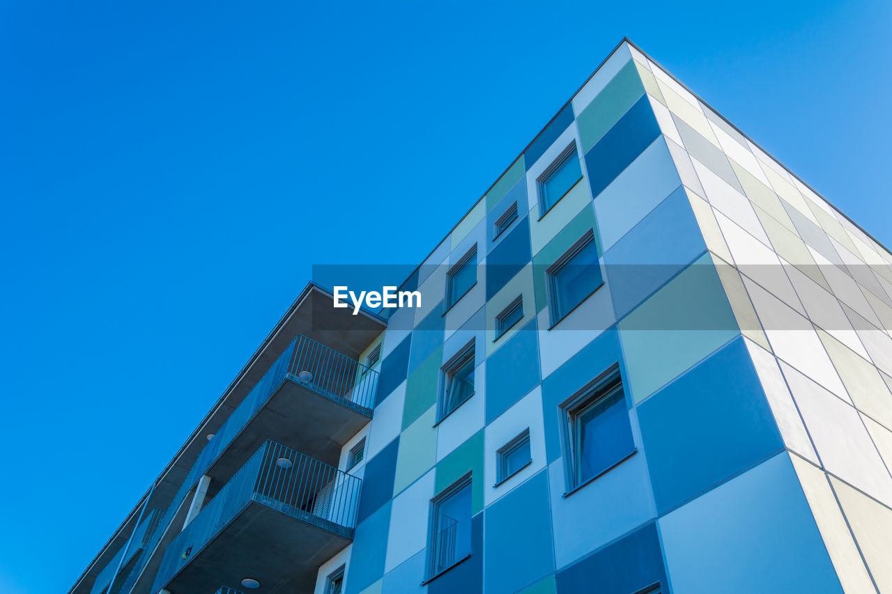 LOW ANGLE VIEW OF MODERN BUILDING AGAINST CLEAR BLUE SKY