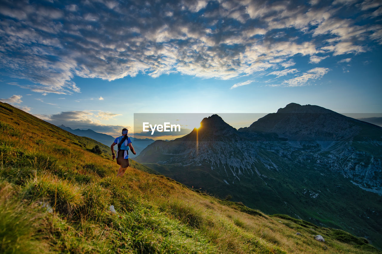 MAN STANDING ON MOUNTAINS AGAINST SKY