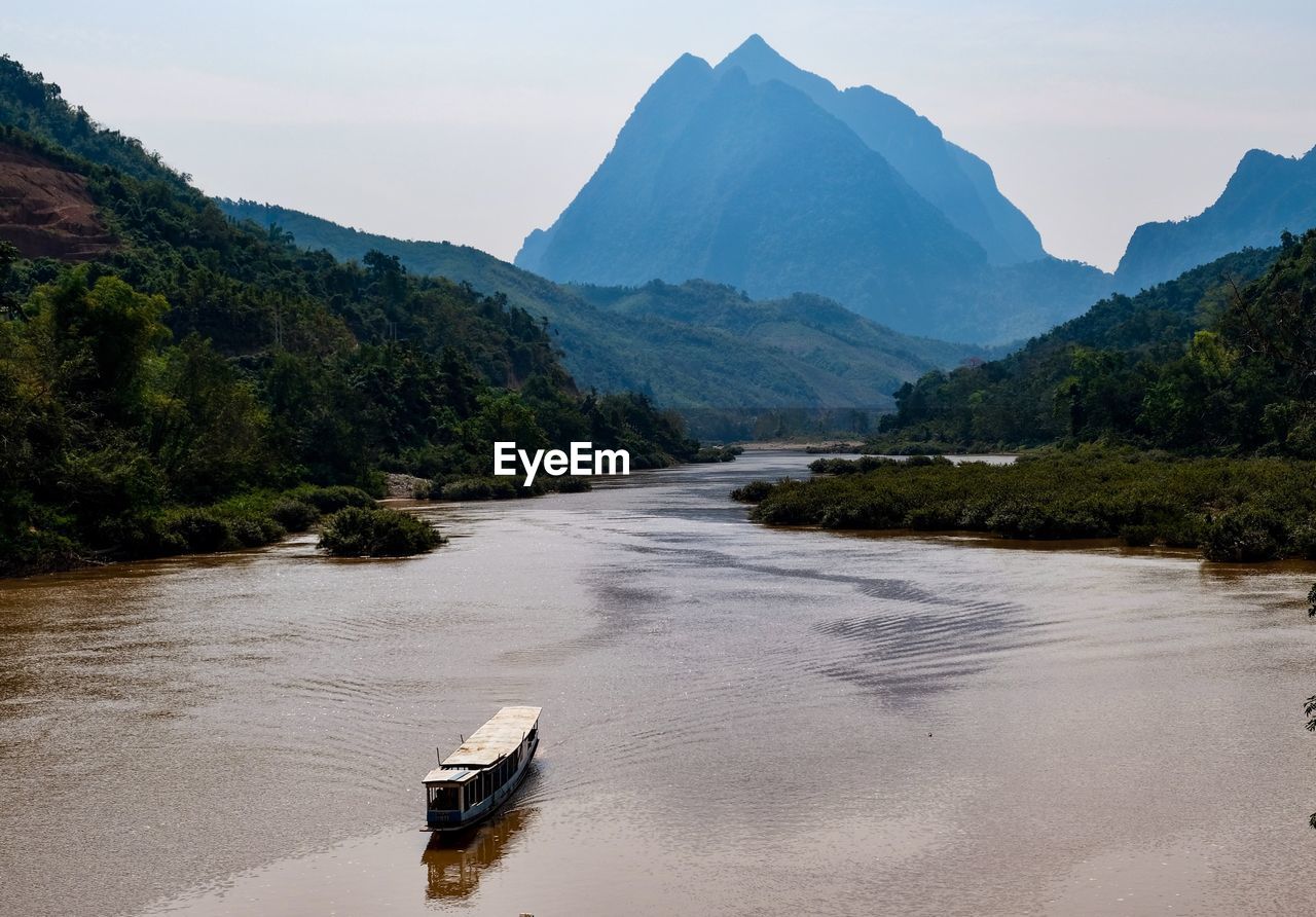 Scenic view of river by mountains against sky