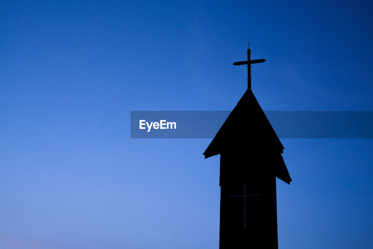 Low angle view of cross on building against blue sky