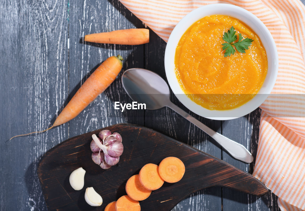 Carrot puree spicy soup on rustic table. autumn vegan menu.  fall  winter comforting food. top view