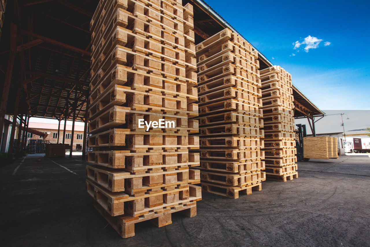 STACK OF WOODEN LOGS AGAINST BUILDINGS