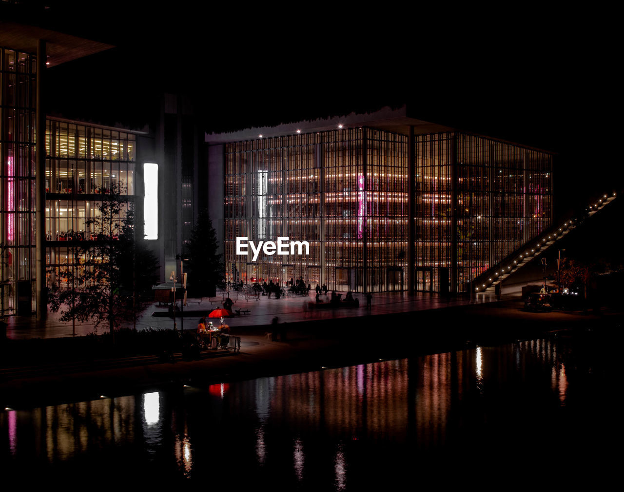 ILLUMINATED BUILDING BY LAKE AT NIGHT