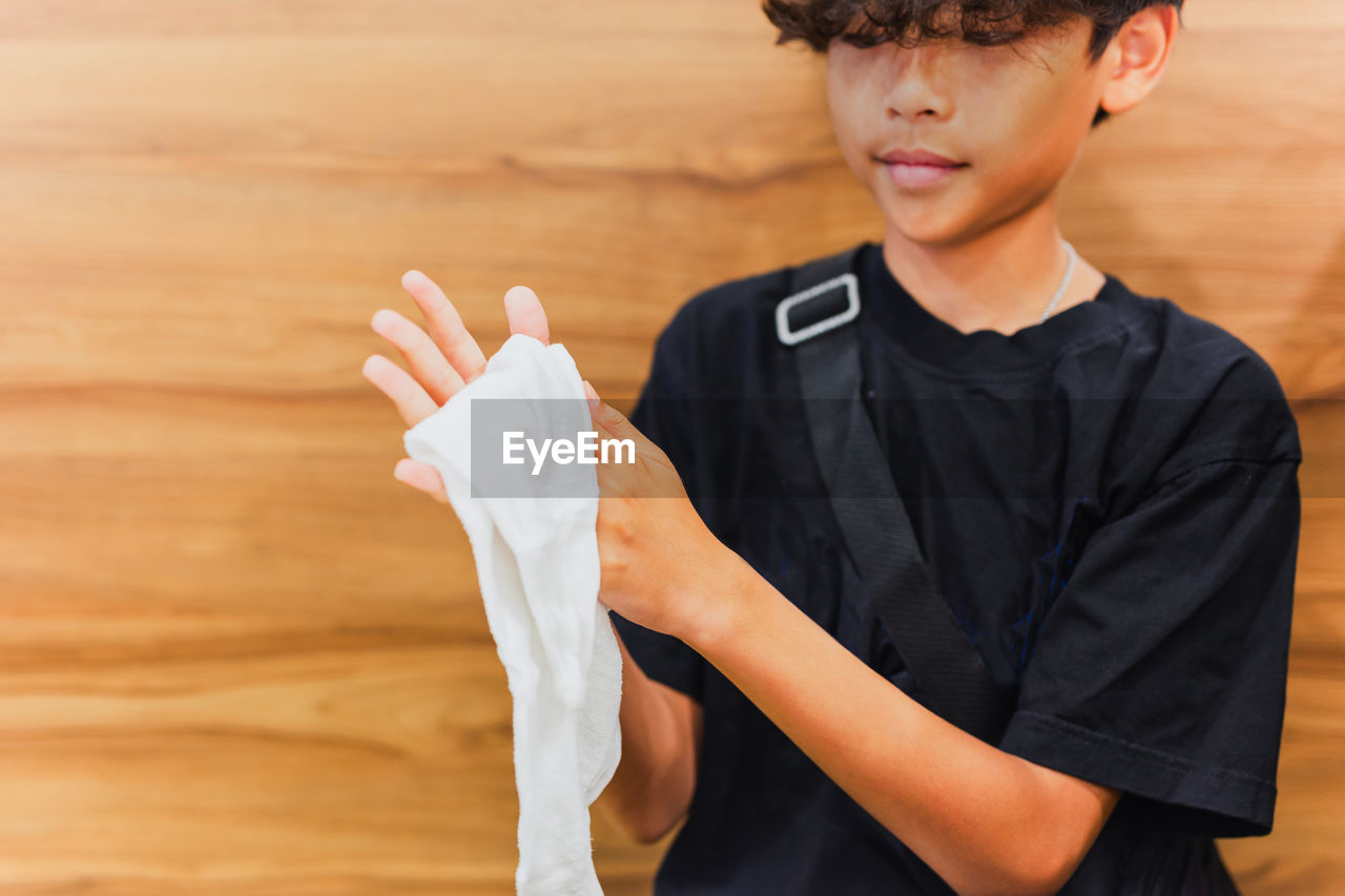 Young boy cleaning hands with a towel in restaurant.