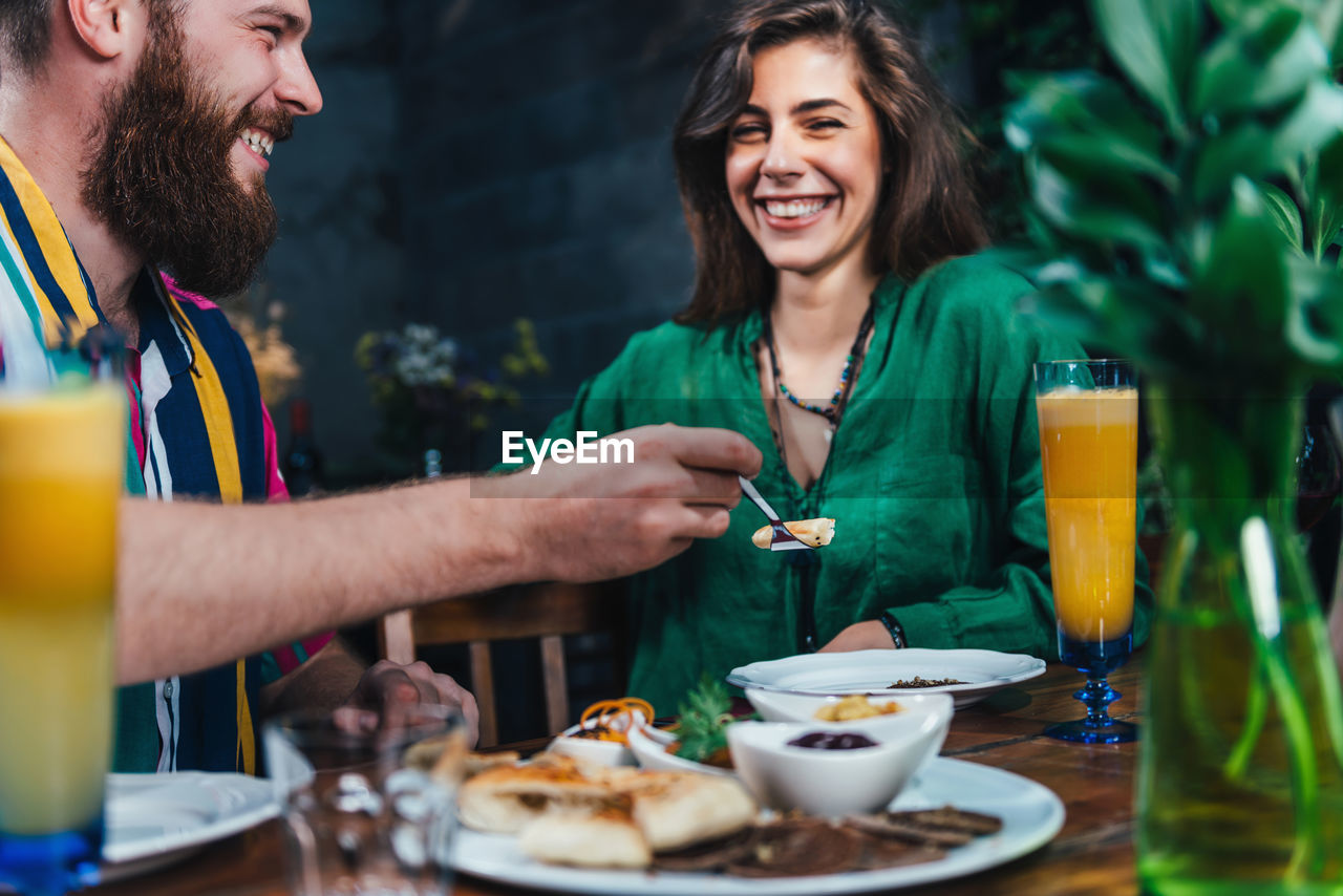 Smiling young couple enjoying lunch at table in restaurant