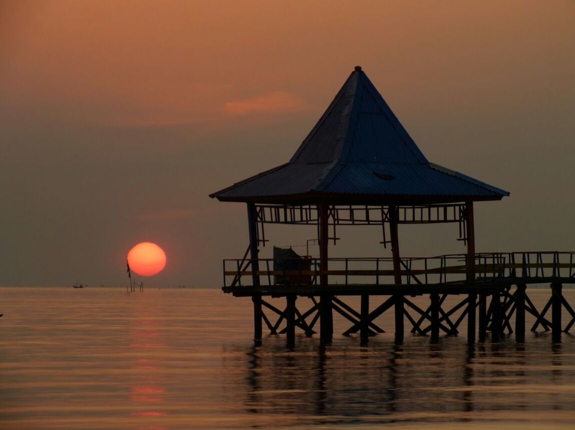 Stilt structure at calm sea during sunset